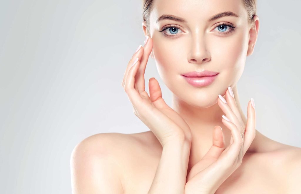 Woman with clear skin touching face.