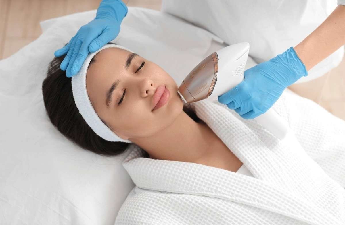 Beautician epilating woman's face in salon, closeup